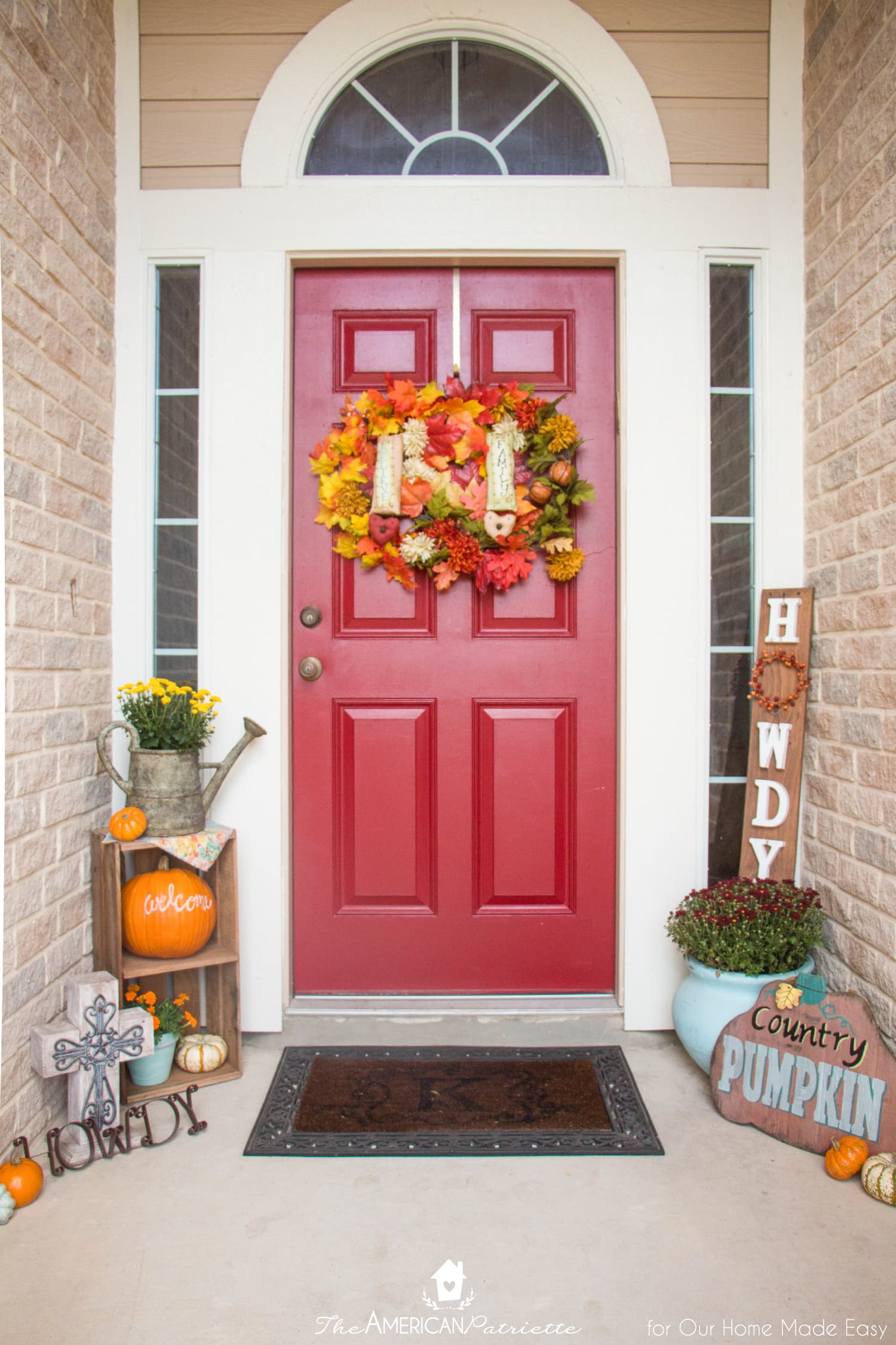 A bright red front door and pops of orange make this fall front porch stand out